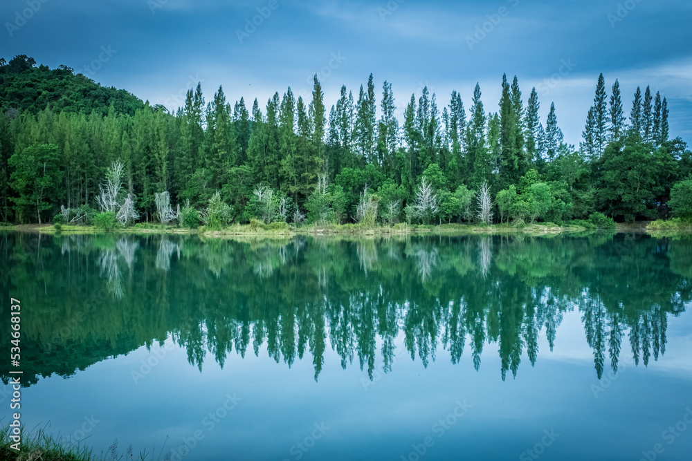 Beautiful view of green pine forest and lake with trees and cloudy blue sky reflection, landscape of old mine Liwong in Chana, Songkhla, Thailand