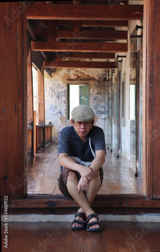 The person sitting on the floor at the door, hugging his knees.  © Monta