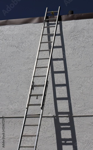 Tall Ladder Leaning Against Wall with Dark Shadow