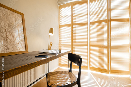 Cozy worplace with wooden table, chair and window blinds on background in bright living room at home photo