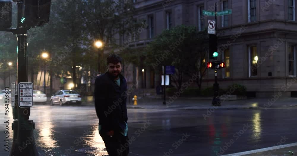 Stormy weather in city downtown, cheerful man crossing the road under strong wind and heavy rain. Tropical Storm Ian in Raleigh, NC Stormy weather in city downtown, cheerful man crossing the road under strong wind and heavy rain. Tropical Storm Ian in Raleigh, NC