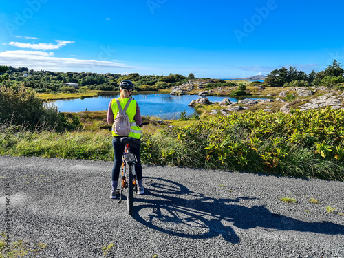 Lady with bicycle taking smartphone photos of a lake by Burtonport, County Donegal, Ireland - Seen from the Railway walk photo