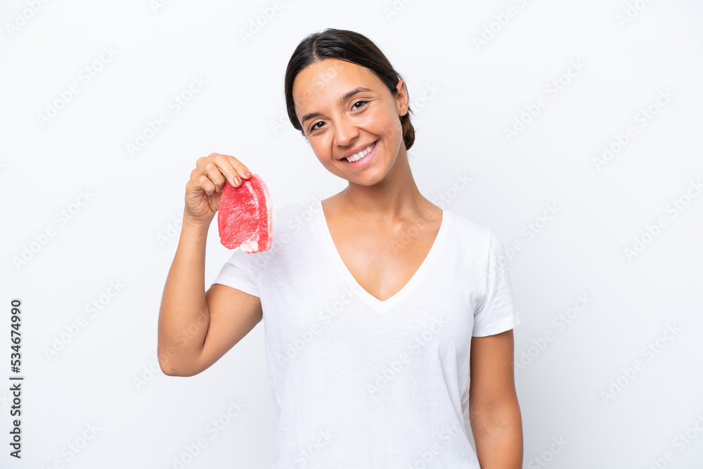 Young hispanic woman holding a piece of meat isolated on white background smiling a lot Young hispanic woman holding a piece of meat isolated on white background smiling a lot