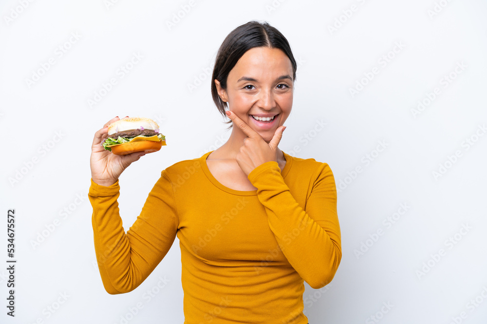 Young hispanic woman holding a burger isolated on white background happy and smiling Young hispanic woman holding a burger isolated on white background happy and smiling