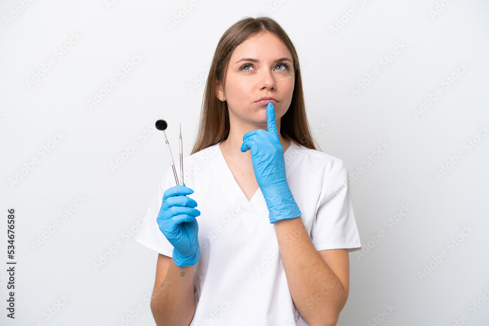 Dentist woman holding tools isolated on white background having doubts while looking up Dentist woman holding tools isolated on white background having doubts while looking up