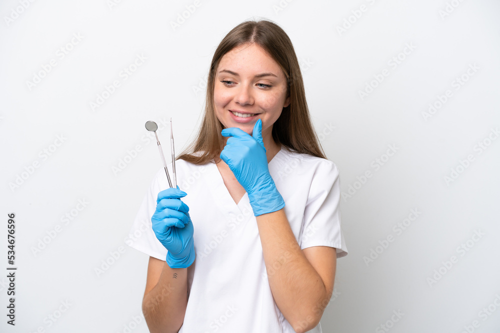 Dentist woman holding tools isolated on white background looking to the side and smiling Dentist woman holding tools isolated on white background looking to the side and smiling