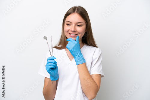 Dentist woman holding tools isolated on white background looking to the side and smiling