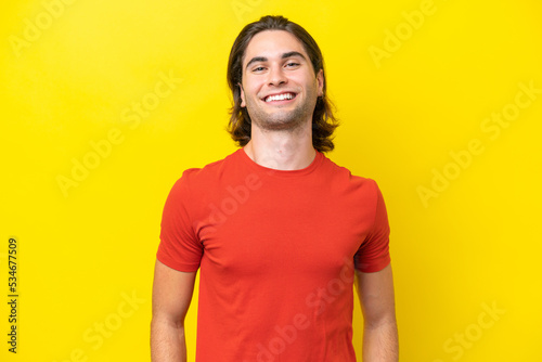 Caucasian handsome man isolated on yellow background laughing