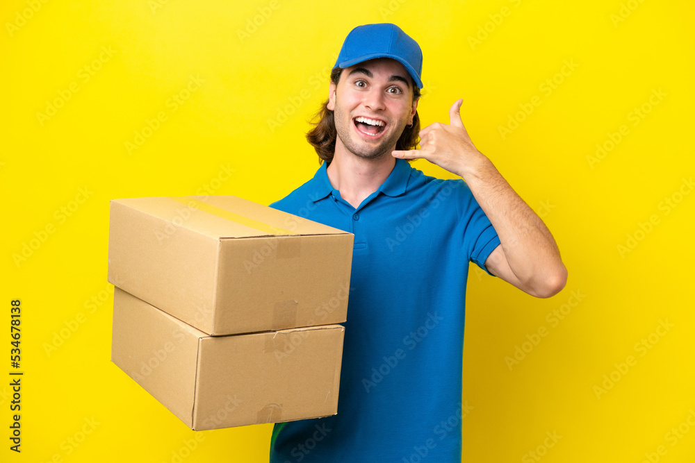 Delivery handsome man isolated on yellow background making phone gesture. Call me back sign Delivery handsome man isolated on yellow background making phone gesture. Call me back sign