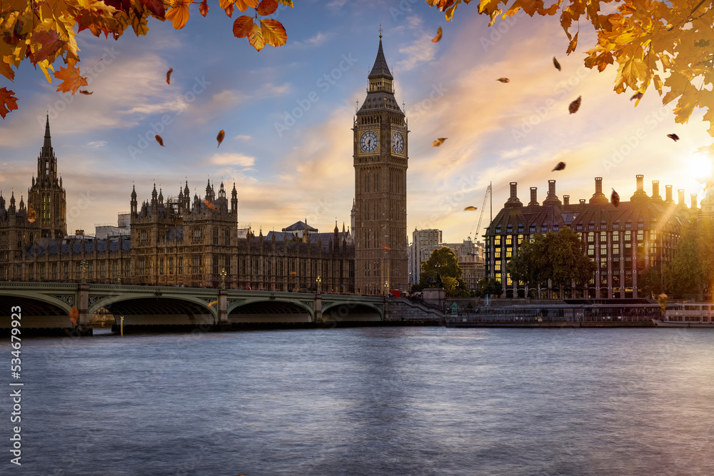 Obraz premium Beautiful autumn view of the Westminster Bridge and palace with Big Ben clocktower in London, golden branches and leaves and soft sunset light