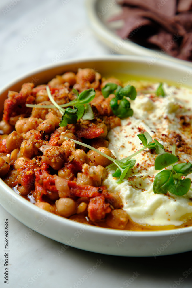 Chickpeas and tomato sofrito with hummus in a white bowl Chickpeas and tomato sofrito with hummus in a white bowl