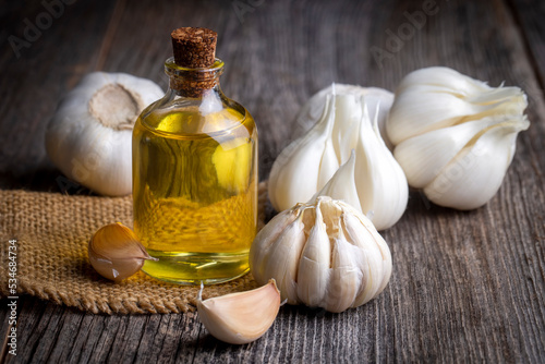Fresh garlic and garlic oil on the wooden background