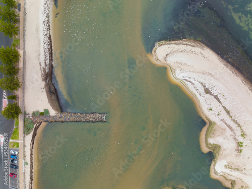 Aerial view of an unusually shaped sand bar near a breakwater on the coast