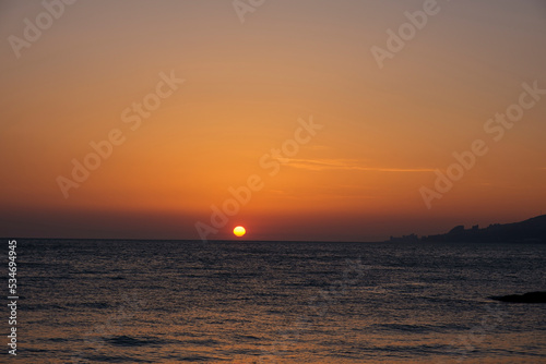 Gorgeous sea sunset landscape. MIrror reflection of dawn on sea surface. Red sun on cloudless sky  apocalypse. Blurred  out of focus