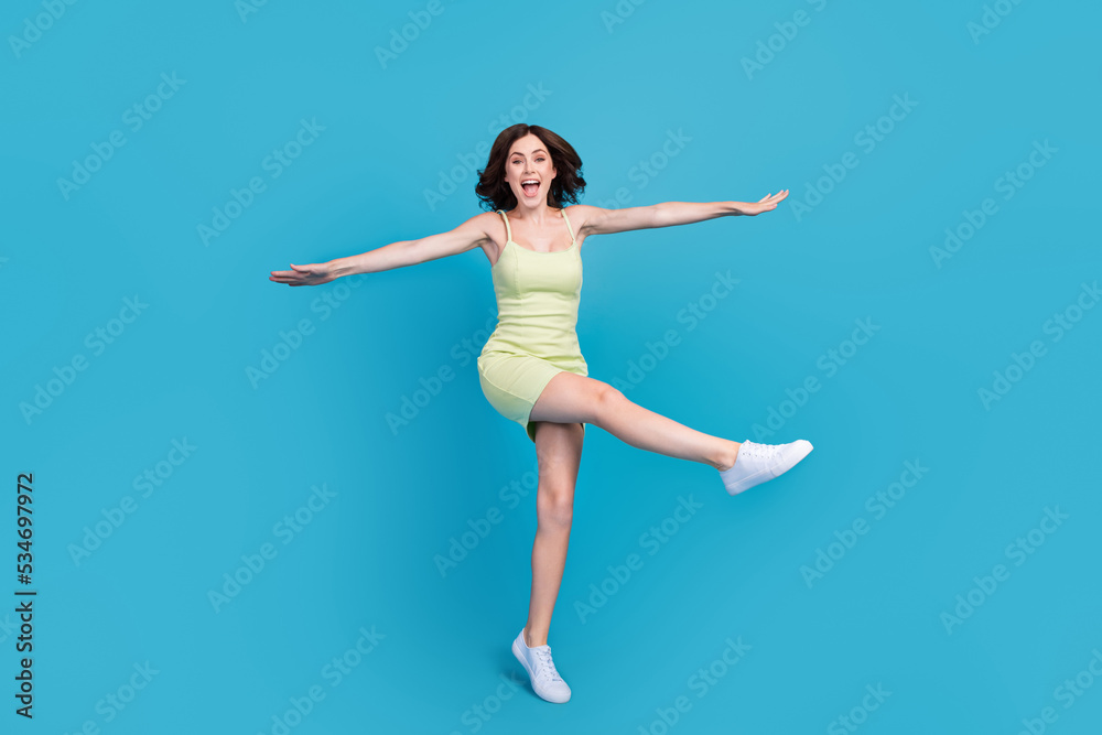 Full length photo of adorable cute lady wear green outfit walking jumping high isolated blue color background