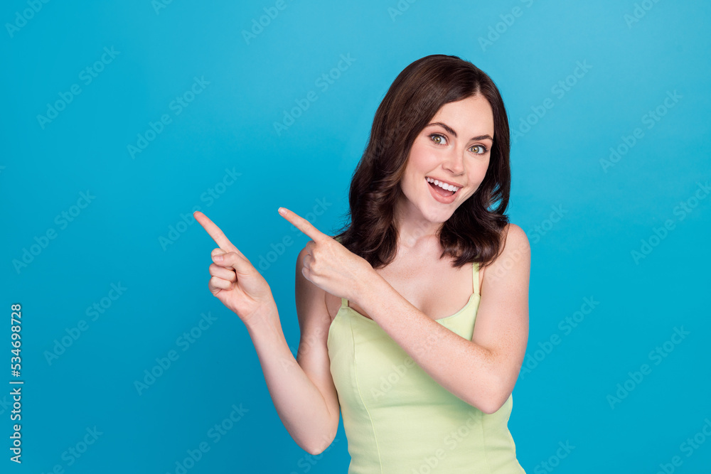 Photo of excited sweet girl dressed green dress pointing fingers empty space isolated blue color background Photo of excited sweet girl dressed green dress pointing fingers empty space isolated blue color background