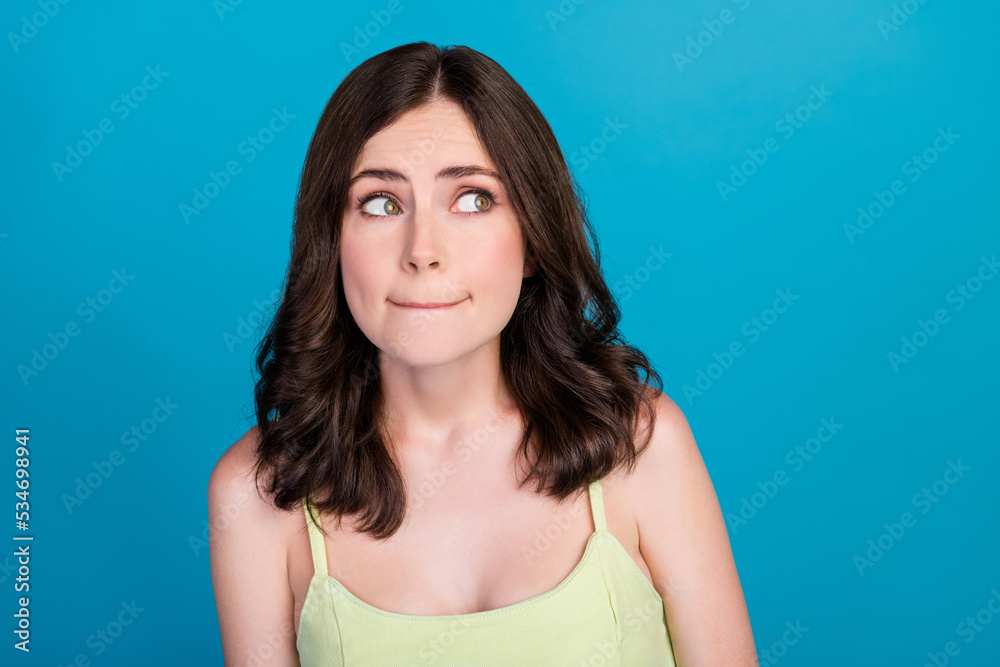 Photo of doubtful unsure lady wear green outfit looking empty space isolated blue color background Photo of doubtful unsure lady wear green outfit looking empty space isolated blue color background