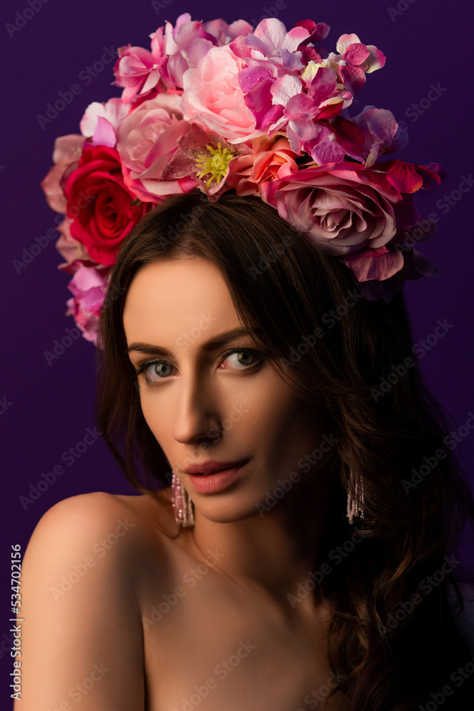 Portrait of an attractive young Ukrainian woman wearing a beautiful wreath of pink roses. Headdress for a girl. Concept wedding style or beauty salon and skin care.