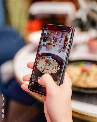 Un homme prend une photo de son repas avec un téléphone dans un restaurant