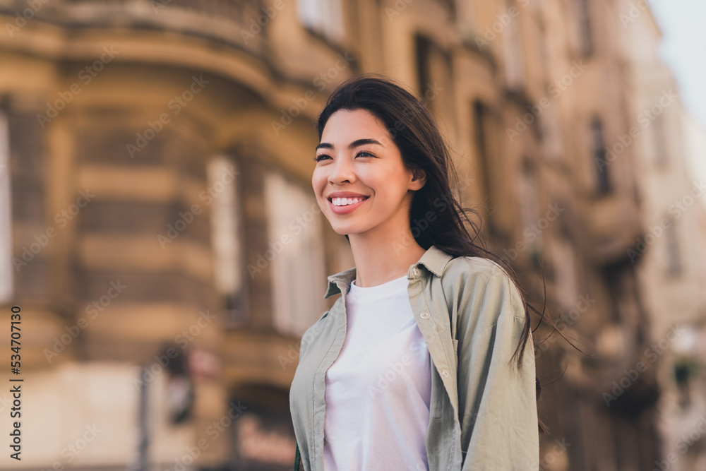 Photo of adorable shiny young asian woman wear khaki shirt enjoying fall sunshine walking city tour outside urban city street