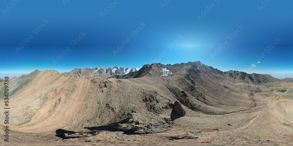 360 panorama of a mountain lake and snowy peaks. A moraine lake with the color of an emerald. Steep rocky cliff. High mountains and ancient glaciers. Blue sky. A band of smog and clear sky is visible