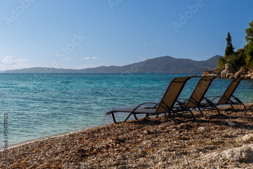 Three chairs are set up on the beach by the sea, good atmosphere, bright sunshine. © MAXSHOT_PL