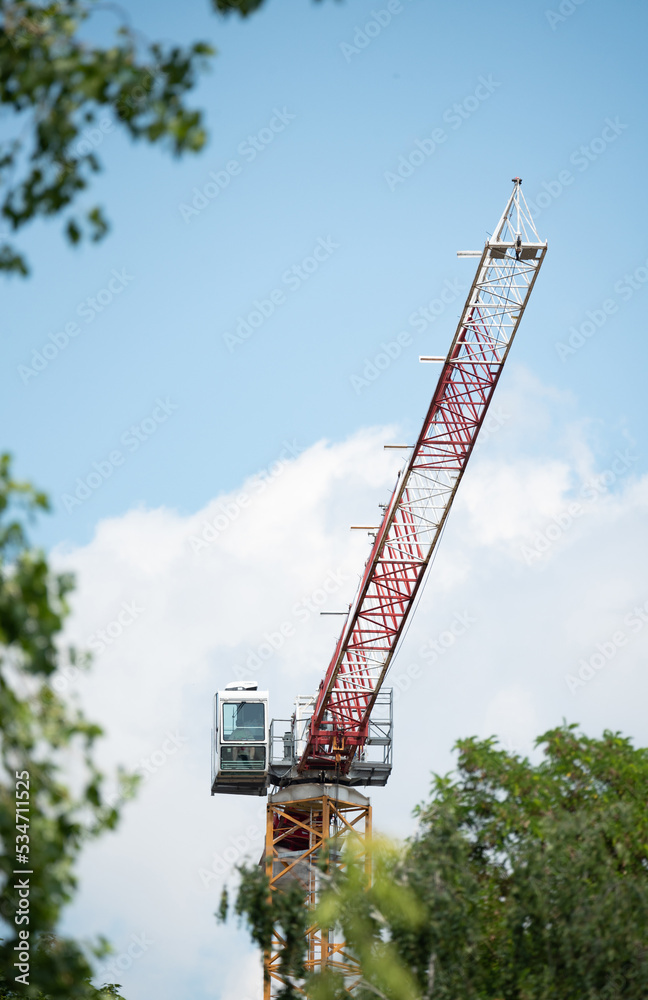Construction crane between the treetops. Construction crane structure and cabin.