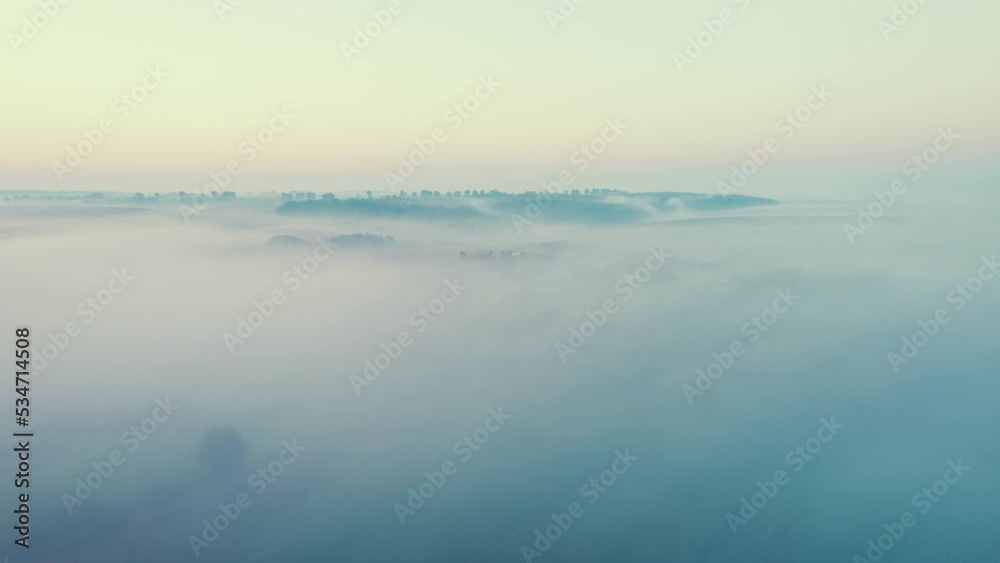 Dense, heavy, thick fog softly covering hills and forests. Sunrise light. Drone aerial bird's eye perspective. Natural phenomenon. High quality 4k footage