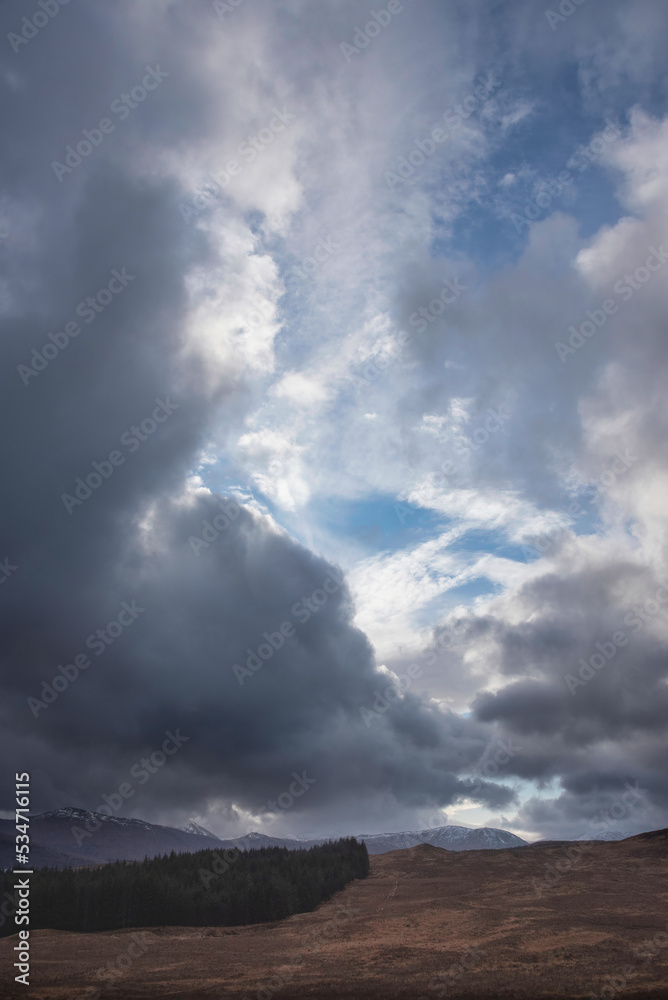 Winter dramatic stormy skies landscape image over snowcapped mountains in Scottish Highlands Winter dramatic stormy skies landscape image over snowcapped mountains in Scottish Highlands