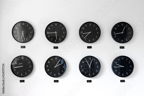 Different times al around the world including Great Britain, Russia and Honk Kong. Eight clocks on wall showing world time zones.