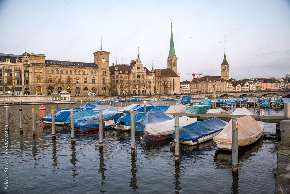 Limmat river in Zurich with boats, and Fraumünster and St. Peter's church in the back