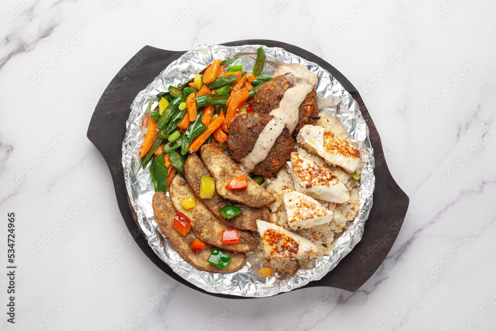 Close-up of veg vrat or fasting or upvas sizzlers with paneer, potatoes carrots wooden plate, served burning hot with fumes at table Close-up of veg vrat or fasting or upvas sizzlers with paneer, potatoes carrots wooden plate, served burning hot with fumes at table
