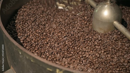 Close up brown coffee bean roasting in a coffee roasting machine with rotating metal arm in 4k.