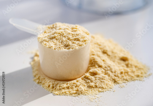Cup of protein powder on white table photo