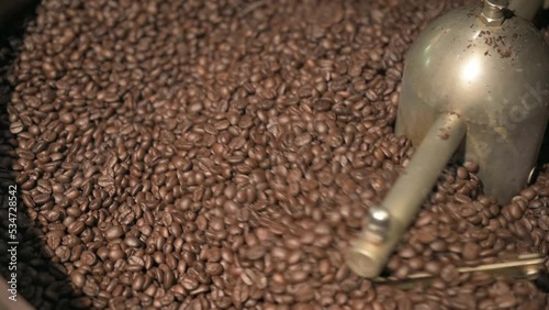 Close up brown coffee bean roasting in a coffee roasting machine with rotating metal arm in 4k.