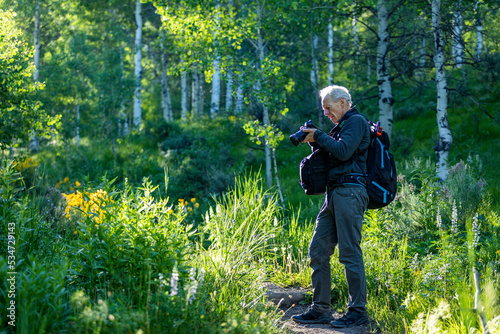 Senior man taking photographs while hiking