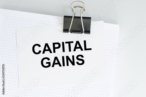 CAPITAL GAINS text on sticker with pen on white background