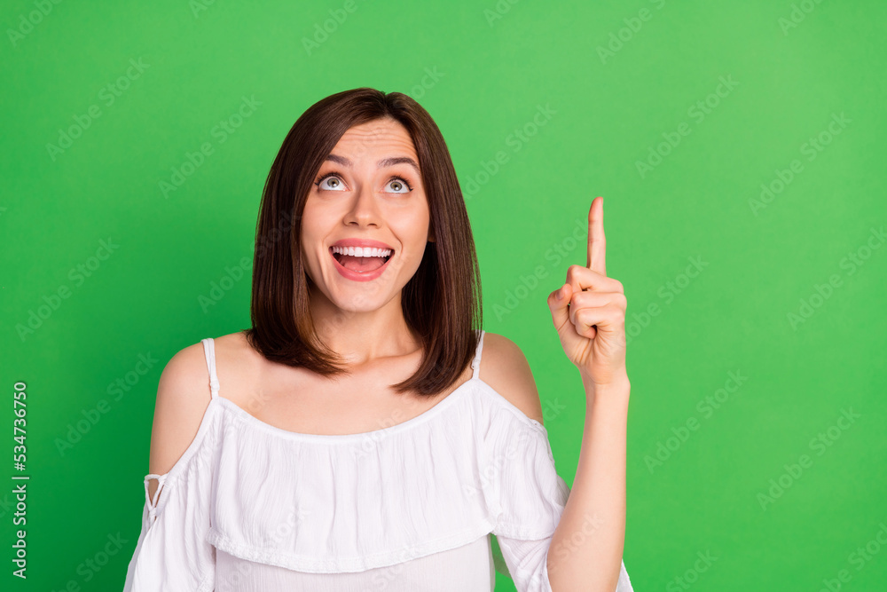 Portrait of positive astonished girl look indicate finger up empty space isolated on green color background Portrait of positive astonished girl look indicate finger up empty space isolated on green color background