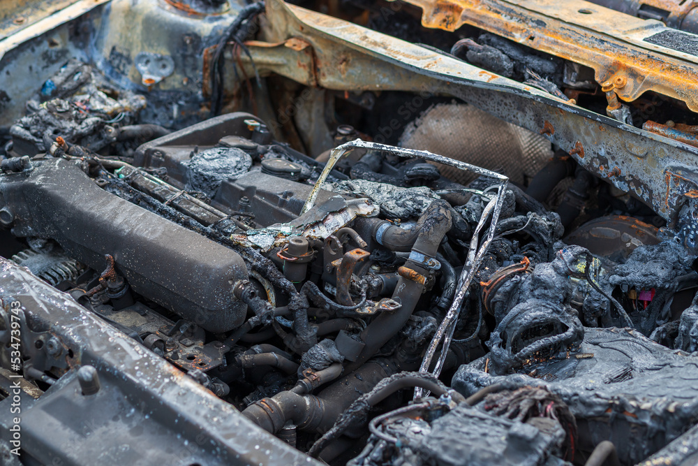 An old rusty car that burned down. A burned-out car stands on the side of the road. Burned out car engine An old rusty car that burned down. A burned-out car stands on the side of the road. Burned out car engine