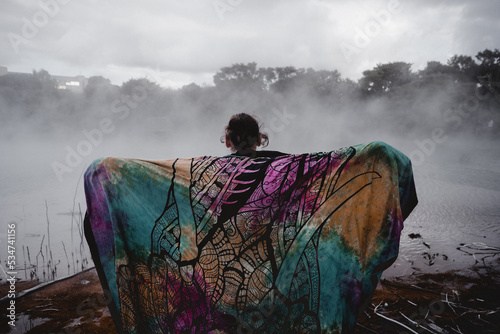 young man from behind covered with a colorful blanket in lake rotorua