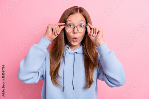 Closeup photo of young funny teenager wear blue hoodie trying new eyeglasses pouted lips shocked unexpected face isolated on pink color background