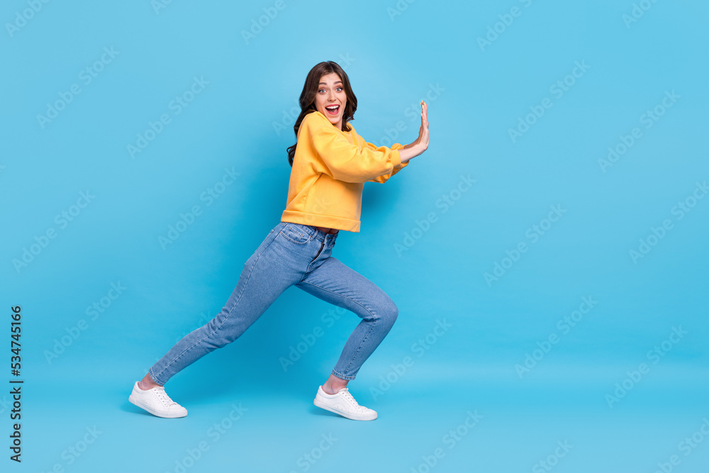 Full length photo of impressed excited lady wear yellow sweater pulling big empty space isolated blue color background Full length photo of impressed excited lady wear yellow sweater pulling big empty space isolated blue color background