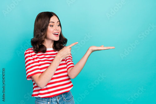 Portrait photo of young pretty woman wear red striped t-shirt finger point hold palm dreamy recommend new product isolated on cyan color background