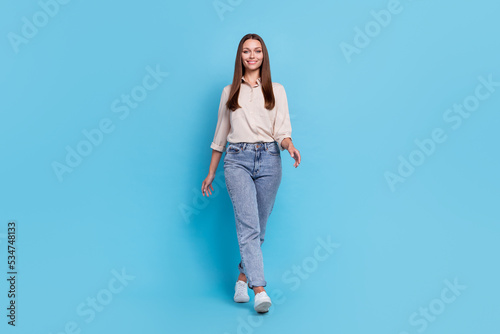Full size photo of optimistic young lady go wear grey shirt jeans shoes isolated on blue color background