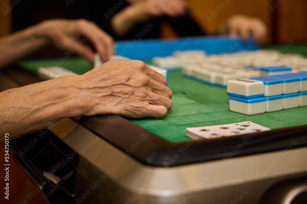 Elderly people playing mahjong, indoor gamble activity at home during spring festival. Elderly people playing mahjong, indoor gamble activity at home during spring festival.