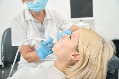 Caucasian woman doctor treats teeth to woman patient
