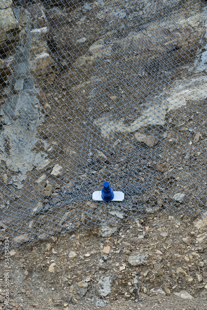 Reinforcing mountain slope with metal mesh and concrete reinforcement, preventing rocks falling on the road. Landslide and rock sliding prevention in Georgia. Cliff erosion control concept. 