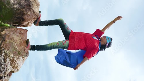 vertical shot girl with superman custume and enjoying by imagining at mountain - concept of childhood lifestyle, inspiration and adventure lifestyle photo