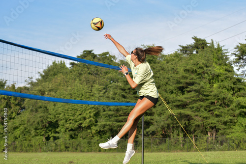 Female volleyball player hitting the ball on a grass doubles game