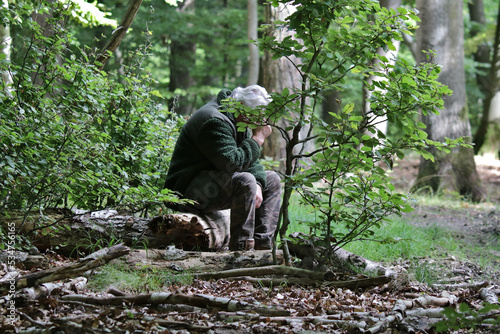alter Mann sitzt allein und verzweifelt im Wald